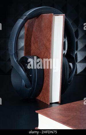 Eine Nahaufnahme eines Hardcover-Buches mit Kopfhörern. Konzept eines Hörbuchs. Stockfoto