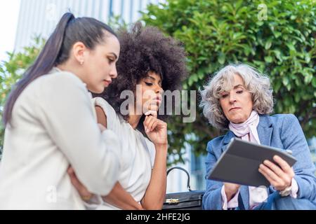 Drei Arbeiterinnen, die in der Stadt Unternehmensinformationen studieren Stockfoto