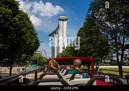 Ausländische Reisende, die auf einer offenen Bustour die üppigen grünen Bäume und den berühmten Marina Bay Sands in Singapur besichtigen. Stockfoto