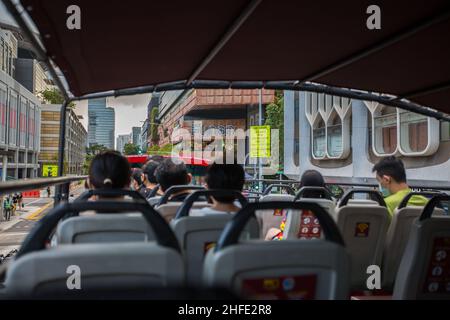 Im Doppeldeckerbus mit offenem Oberdeck, gefüllt mit Touristen, mit Blick auf die Funan Mall, die entlang der North Bridge Road fährt. Singapur. Stockfoto