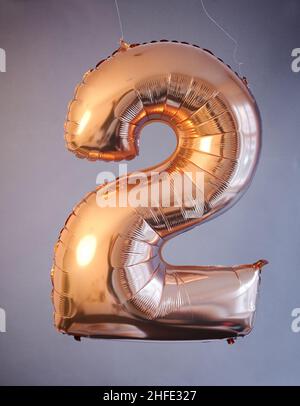 Berlin, Deutschland. 14th Januar 2022. ABBILDUNG - Ein goldener Ballon in Form der Zahl 2 hängt vor einem grauen Hintergrund. (Posierte Szene) im Februar dieses Jahres gibt es mehrere Tage, die für ein besonderes Hochzeitsdatum geeignet sind, darunter die Alkoholzahlendaten, d.h. 2.2.22 und 22,2.22. Quelle: Annette Riedl/dpa/Alamy Live News Stockfoto