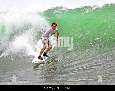 Ein kaukasischer Surfer, der eine große Welle am Airport Reef in Tuban, Bali in Indonesien, reitet. Stockfoto