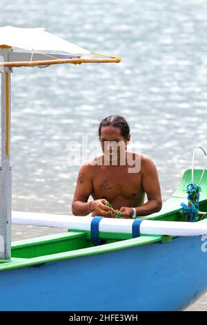 Ein einheimischer Balinese, der seine perahu oder sein Boot am Tuban Beach, Bali in Indonesien, hält. Stockfoto