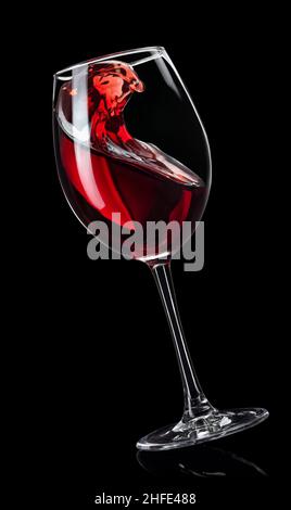 Spritzender Rotwein im Glas isoliert auf schwarz Stockfoto