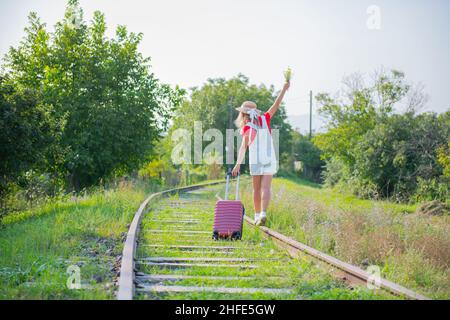 Ein Mann in einem Hut und einem Koffer geht entlang der Versteppungen Stockfoto