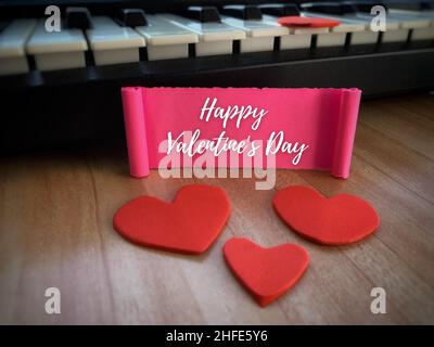 Happy Valentine's Day Label auf pinkem Papier mit Herzform und Tastaturhintergrund. Stockfoto