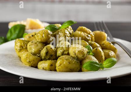 Heiße cremige Kartoffelgnocchi mit Pesto-Sauce, frischem Basilikum und Parmesan. Geringe Tiefenschärfe. Stockfoto