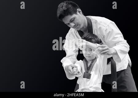 Taekwondo Master Black Belt Lehre kid Guard auf schwarzem Hintergrund zu kämpfen Stockfoto