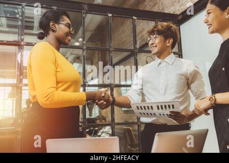 Schwarze afrikanische Geschäftsfrauen angeheuert Hand schütteln Deal Arbeit mit asiatischen Chef genießen die Zusammenarbeit Konzept. Stockfoto
