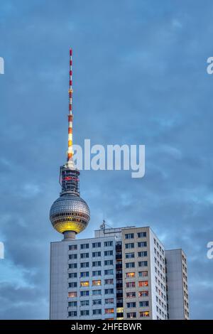 Der berühmte Fernsehturm von Berlin in der Abenddämmerung mit einem typischen DDR-Fertighaus Stockfoto