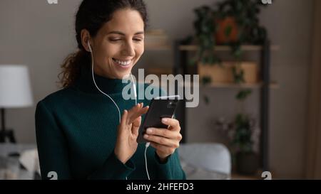 Glückliche junge schöne Frau in Ohrhörern mit Smartphone. Stockfoto