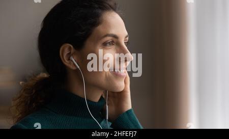 Glückliche junge Frau, die Musik in den Kopfhörern hört. Stockfoto