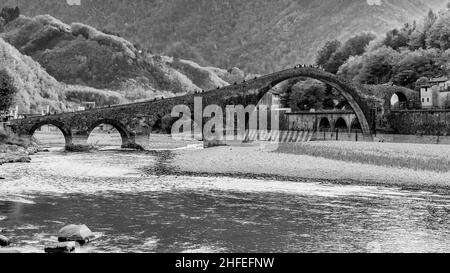 Schwarz-Weiß-Ansicht des Flusses Serchio, der unter der Ponte della Maddalena oder del Diavolo, Borgo a Mozzano, Lucca, Italien fließt Stockfoto