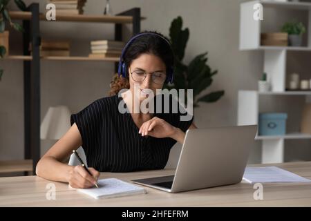 Glückliche interessierte tausendjährige Frau, die auf Online-Kursen studiert. Stockfoto