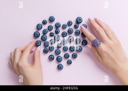 Weibliche Hände mit schöner Maniküre machen Herzform mit Beeren Stockfoto