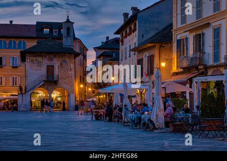 Piazetta Ernesto Ragazzorli, der Hauptplatz von Orta San Giulio, mit Restaurants und Geschäften in der Umgebung, die nachts beleuchtet sind. Stockfoto