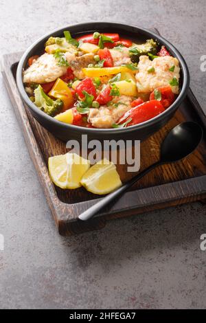 Dicke Fischsuppe mit Paprika, Kartoffeln, Erbsen, Zwiebeln, Brokkoli und Tomaten in einer Schüssel auf dem Tisch. Vertikal Stockfoto