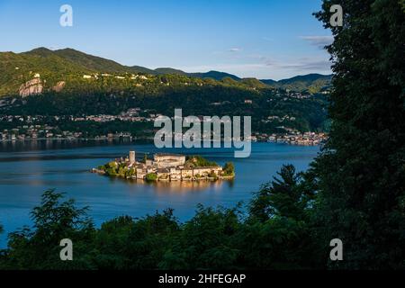Luftaufnahme vom Sacro Monte auf der Insel St. Julius mit der Basilica di San Giulio in der Mitte des Orta-Sees, in der Ferne die umliegenden Berge. Stockfoto