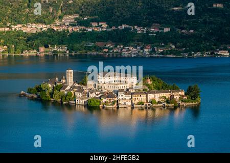 Luftaufnahme vom Sacro Monte auf der Insel St. Julius mit der Basilica di San Giulio in der Mitte des Orta-Sees, in der Ferne die umliegenden Berge. Stockfoto
