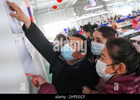 (220116) -- YUTIAN, 16. Januar 2022 (Xinhua) -- Maynurhan Amang (2nd R) und Abudulezizi Maisedi (3rd R) überprüfen ihr Gehalt an der Produktionsbasis von Erke im Industriepark Tianjin im Bezirk Yutian, im Nordwesten der Autonomen Region Xinjiang, Uygur, am 14. Januar 2022. Yutian County, einst ein von Armut gebeuteltes Gebiet in Xinjiang, hat die Entwicklung arbeitsintensiver Industrien wie Textil-, Bekleidungs- und Sockenherstellung verstärkt. Im Tianjin Industriepark in Yutian wurde am 1. Januar 2022 eine Produktionsbasis der chinesischen Sportmarke Erke in Betrieb genommen, die mehr als 500 Arbeitsplätze für Einheimische bot. Ma Stockfoto