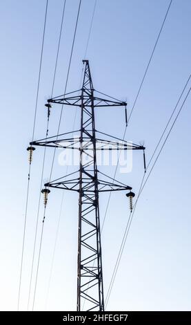 Hochspannungsleitungen, Pfosten oder Turm vor dem Hintergrund eines schönen Himmels. Sequenziell bestellte Hochenergie-Pylone Stockfoto