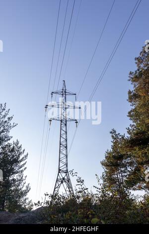 Hochspannungsleitungen, Pfosten oder Turm vor dem Hintergrund eines schönen Himmels. Sequenziell bestellte Hochenergie-Pylone Stockfoto