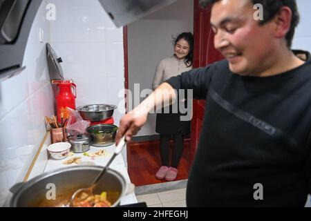 (220116) -- YUTIAN, 16. Januar 2022 (Xinhua) -- Abudulezizi Maisedi (R) kocht beim Plaudern mit Maynurhan Amang in ihrer Wohnung im Tianjin Industriepark im Bezirk Yutian, nordwestlich der Autonomen Region Xinjiang Uygur in China, 13. Januar 2022. Yutian County, einst ein von Armut gebeuteltes Gebiet in Xinjiang, hat die Entwicklung arbeitsintensiver Industrien wie Textil-, Bekleidungs- und Sockenherstellung verstärkt. Im Tianjin Industriepark in Yutian wurde am 1. Januar 2022 eine Produktionsbasis der chinesischen Sportmarke Erke in Betrieb genommen, die mehr als 500 Arbeitsplätze für Einheimische bot. Maynurhan Amang Stockfoto