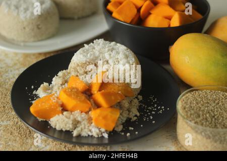 Gedünsteter Hirsemehlkuchen oder hirseputtu mit Mangoscheiben und Kochbananen. Eine Vielzahl von Kerala Reis Dampfkuchen mit Scheckenhof Stockfoto