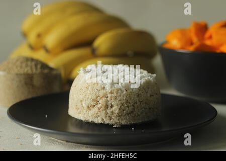 Gedünsteter Hirsemehlkuchen oder hirseputtu mit Mangoscheiben und Kochbananen. Eine Vielzahl von Kerala Reis Dampfkuchen mit Scheckenhof Stockfoto