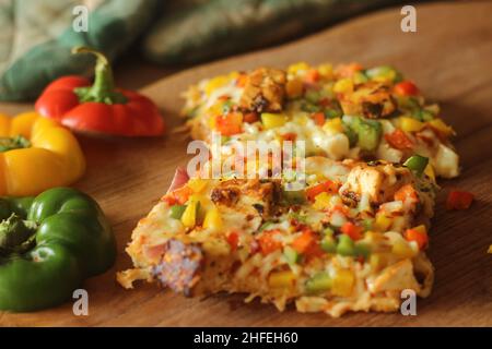 Rechteckige Scheiben selbstgebackener Pizza mit Paneer, Mozzarella-Käse, rot-gelb-grünen Kapsikken und Zwiebeln. Gebacken in einem rechteckigen Tablett Stockfoto