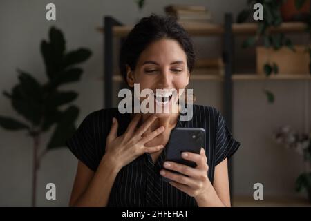 Emotionale glückliche junge Frau feiert online Lotterie gewinnen. Stockfoto