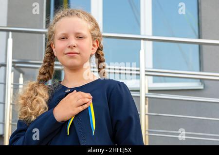 Schulmädchen hält Hand auf Herz! patriot, stolzes Mädchen, das Konzept des Stolzes. Das Konzept des Stolzes als alles andere, Patriotismus . Nationale Farben der Ukraine, Stockfoto