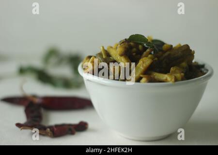 Kleine rohe Bananenscheiben mit Schalotten und Gewürzen umrühren. Die rohen Bananenscheiben sind dünn und lang. Beliebte Beilage für Mahlzeiten in Kerala häufig c Stockfoto