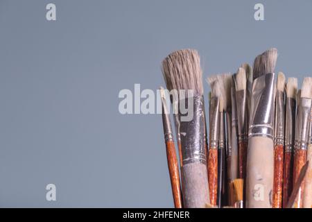 Werkzeuge der Kreativität - eine Reihe von grungigen Malers Pinsel auf schlichtem blauen Hintergrund Stockfoto