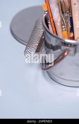 Werkzeuge der Kreativität - eine Reihe von grungigen Pinsel des Malers in einem Metalleimer auf blauem Hintergrund Stockfoto