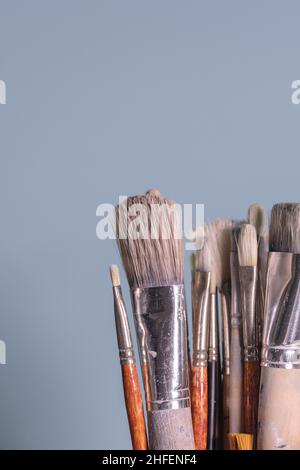 Werkzeuge der Kreativität - eine Reihe von grungigen Malers Pinsel auf schlichtem blauen Hintergrund Stockfoto