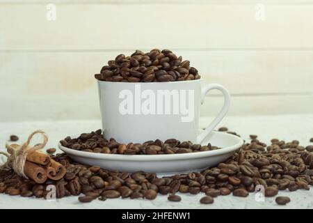 Geröstete Arabica-Kaffeebohnen in einer weißen Tasse. Die Tasse ist mit Kaffeebohnen gefüllt Stockfoto
