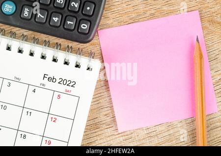 Unbeschriftete Haftnotiz auf dem Tischkalender vom 2022. Februar auf Holzhintergrund für Ihren Text. Stockfoto