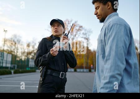 Weiblicher Polizist, der das Ausweisdokument der männlichen Passanten überprüft Stockfoto