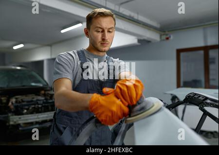 Militärangehöriger beim Polieren von Karosserieteilen in der Werkstatt Stockfoto