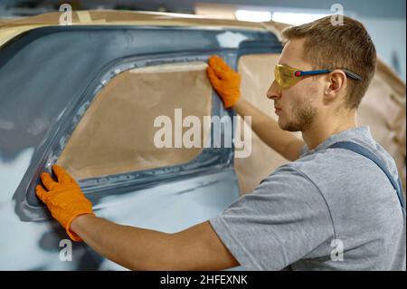 Maler, der Haftpapier zum Schutz des Autos aufgibt Stockfoto