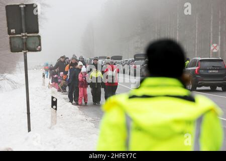 Hellenthal, Deutschland. 16th Januar 2022. Schneetouristen laufen an den Autos vorbei, die auf der Straße geparkt sind, zu den Pisten im Ski- und Schildbereich am Weißen Stein, während die Parkplätze bereits belegt sind. Zahlreiche Besucher sind in der verschneiten Eifel draußen, obwohl die Lifte geschlossen sind. Kredit: David Young/dpa/Alamy Live Nachrichten Stockfoto