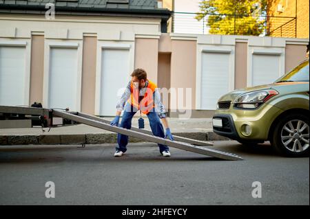 Arbeiter, der die Plattform des Abschleppwagens für das Auto vorbereitet Stockfoto