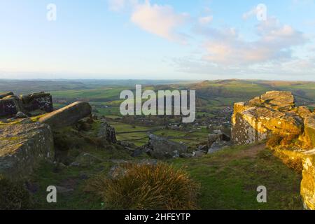 An einem nebligen Wintermorgen offenbart eine Lücke zwischen den Steinfelsen die Landschaft von Derbyshire weit unten. Stockfoto