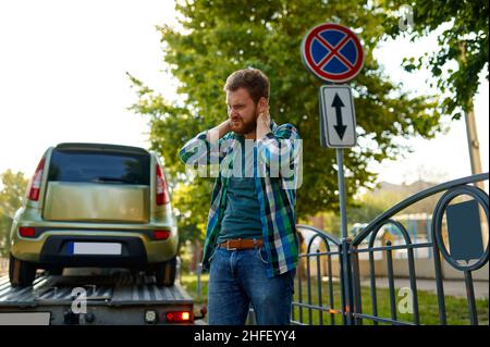 Trauriger Mann und Evakuierung falsch geparktes Auto Stockfoto