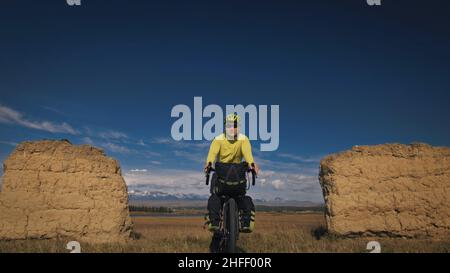 Der Mann reist auf gemischtem Terrain mit Bikepacking. Die Reise des Reisenden mit Fahrradtaschen. Sport Tourismus Bikepacking. Stockfoto