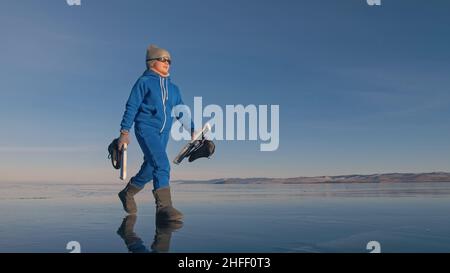 Das Kind trainiert auf Eisschnelllauf. Das Mädchen Schlittschuhe im Winter in Sportbekleidung, Sportbrille, Anzug. Zeitlupe im Freien. Stockfoto