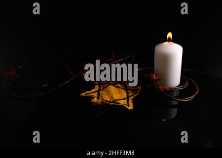 Holocaust-Gedächtnistag. ARBED Draht und brennende Kerze auf schwarzem Hintergrund Stockfoto