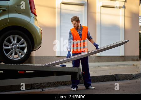 Arbeiter, der die Plattform des Abschleppwagens für das Auto vorbereitet Stockfoto