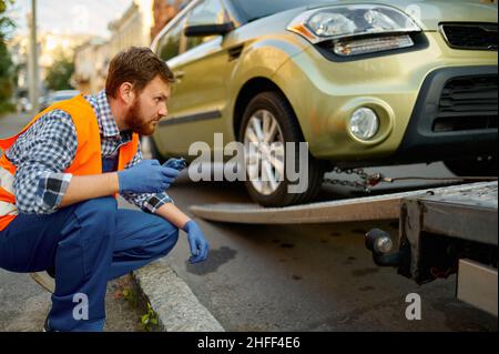 Männlicher Straßenarbeiter, der den Ladevorgang des Fahrzeugs überwacht Stockfoto